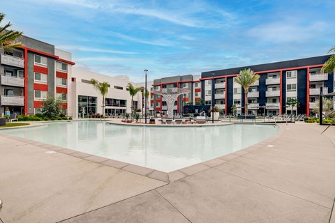 A large swimming pool in front of a building with a red and white exterior.